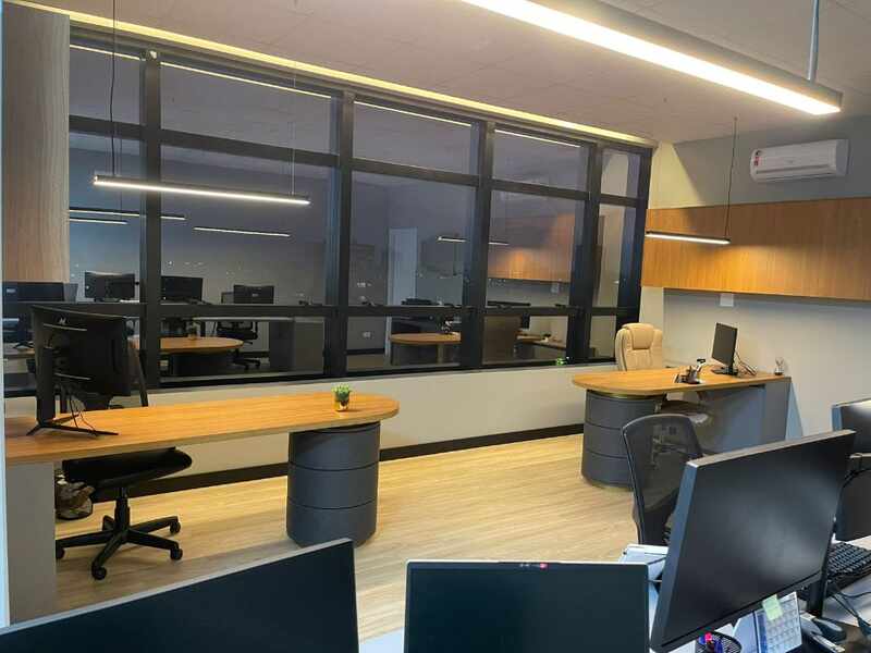 Escritório Melliorem - Ambiente de trabalho noturno com estações e vista da cidade